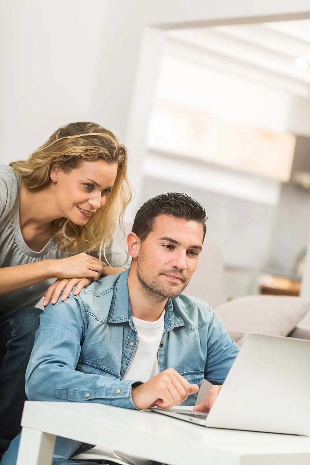Happy young couple in their living room with a laptop
