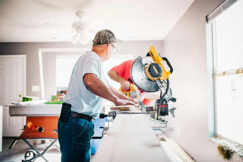 Factors To Look For When Working With Whole House Remodeling Contractors Near Me 3 contractor cutting wood using electric saw