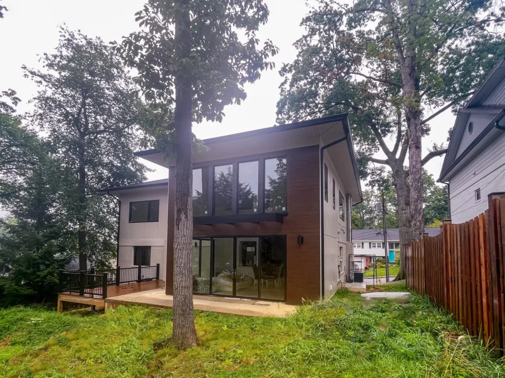 Modern home addition in Arlington, VA with large windows, wood paneling, and a deck in the backyard.